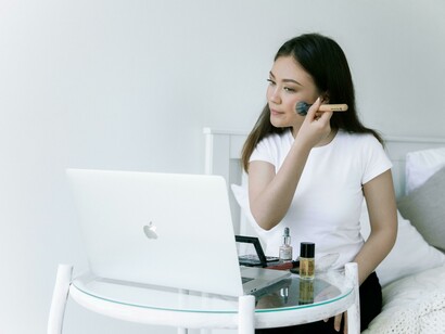 Mujer componiendo su rostro frente a la computadora