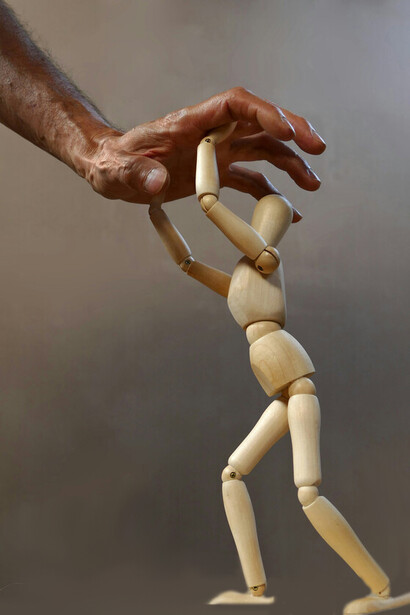 Figurine controlled by a hand, symbolic of oppression 