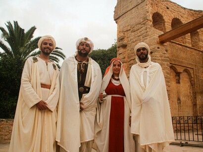 A group of people in distinctive traditional garments and head coverings, reflecting the diversity of cultural expression within a shared heritage