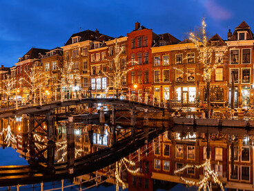 Warm Christmas lights reflect beautifully on a canal in Leiden, Netherlands