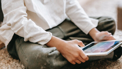 Mãoszinhas manuseiam tablet enquanto brinca com jogo