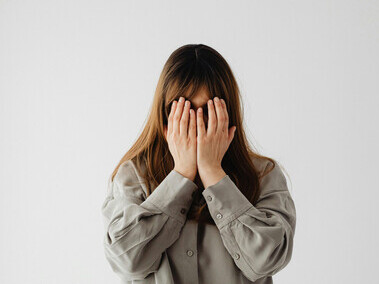 A woman in a gray long-sleeve shirt covering her face — capturing the tension between resistance and growth, and the quiet strength of human resilience