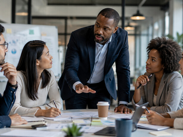 A team leader facilitating an open discussion among colleagues, representing the value of dialogue in overcoming workplace divisions