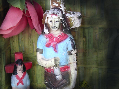 Se arrodilló frente al altar del Gauchito Gil. De las ramas de los árboles que envolvían el ambiente colgaban cintas rojas hasta las raíces. Vista más cercana del santuario del Gauchito Gil, Argentina