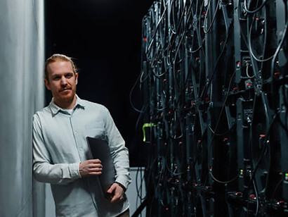 Technician holding a laptop while looking at an LED wall in a server room