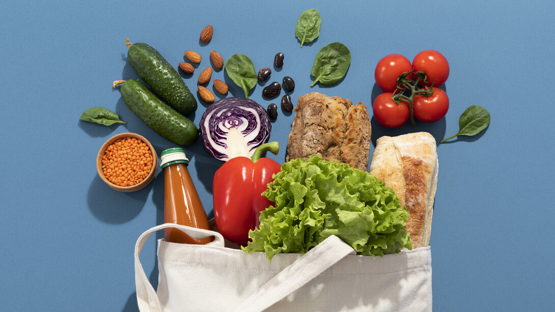 Una borsa della spesa in tela piena di prodotti freschi come verdure, frutta, pane e legumi