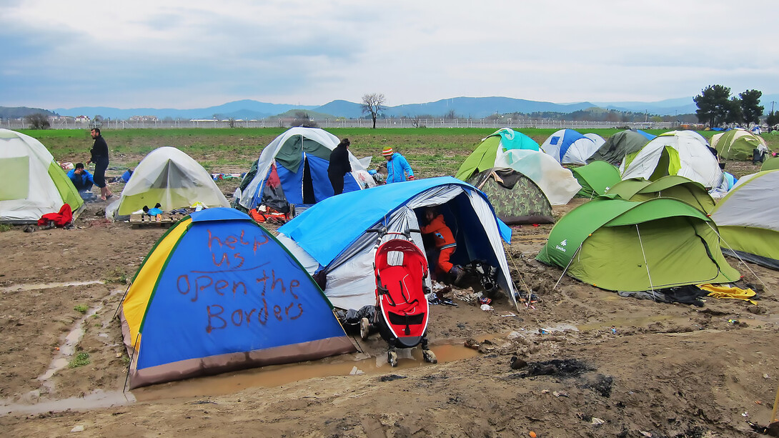 Tents in Idomeni, Greece, with a plea for help to open the borders, reflecting the desperation and hopes of refugees amid a humanitarian crisis