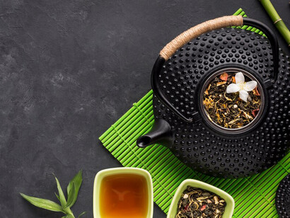 A cup of herbal tea with dried ingredients set out on a green placemat
