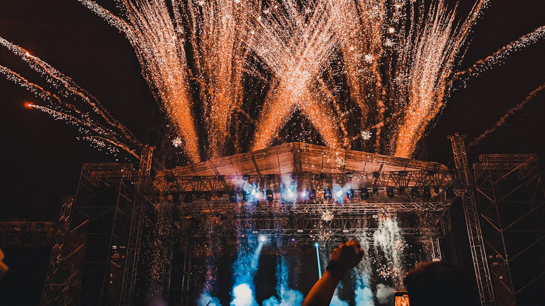 The crowd comes alive under the lights, hands in the air, fully immersed in the energy of the night