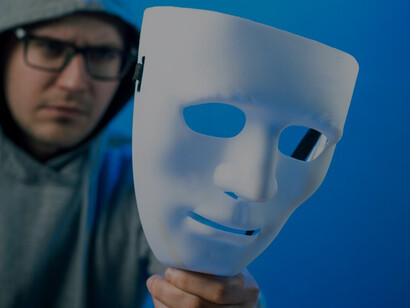 An individual using a mask to obscure their identity online, representing the anonymity prevalent on the internet