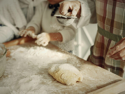 Hands dusting flour over fresh dough evoke the freedom of working from home, where you can pause midday to bake wholesome meals and nourish both body and mind