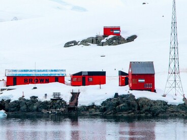 Estación de investigación roja ubicada en el paisaje helado de la Antártida junto al mar, que muestra la exploración remota