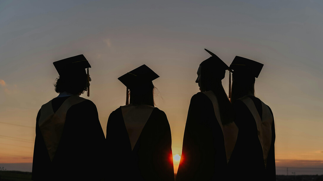 Four newly graduates stare peacefully at the horizon, asking themselves what the next step is