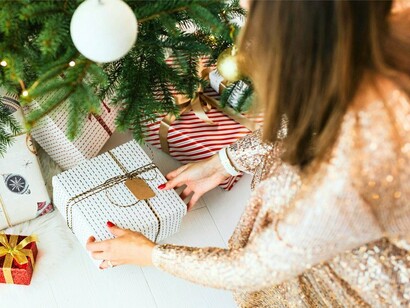A woman carefully arranging Christmas gifts, representing the thoughtfulness and care at the heart of Christmas celebrations