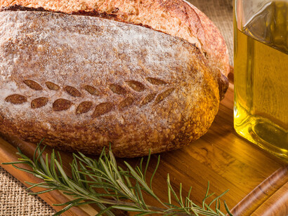 Pão de fermentação natural, um ramo de alecrim e um vidro de azeite