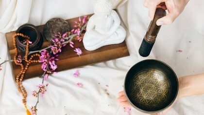 A person preparing to play a Tibetan singing bowl, surrounded by elements of mindfulness and meditation