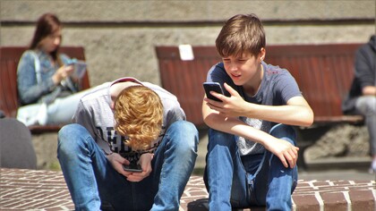 Alunos adolescentes de uma escola usam o celular durante o intervalo