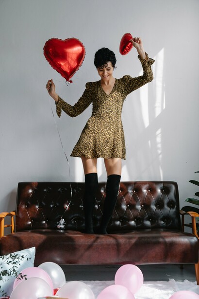 A woman smiling and standing on a leather couch, celebrating self-love and positivity in her life