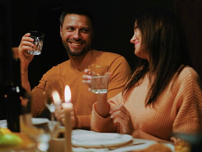 Duas pessoas compartilham uma refeição enquanto trocam olhares e conversam à mesa. As melhores lembranças muitas vezes nascem durante encontros simples ao redor da comida