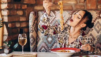A woman savors delicious pasta in a cozy Italian restaurant, immersing in the ambiance of traditional dining