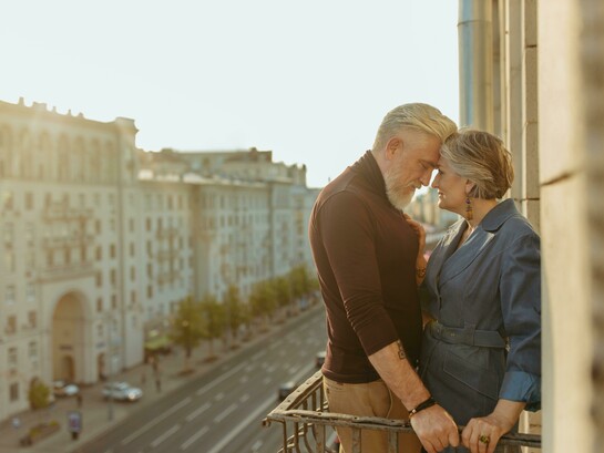An elderly couple on a balcony, captured in a quiet moment as they share a kiss