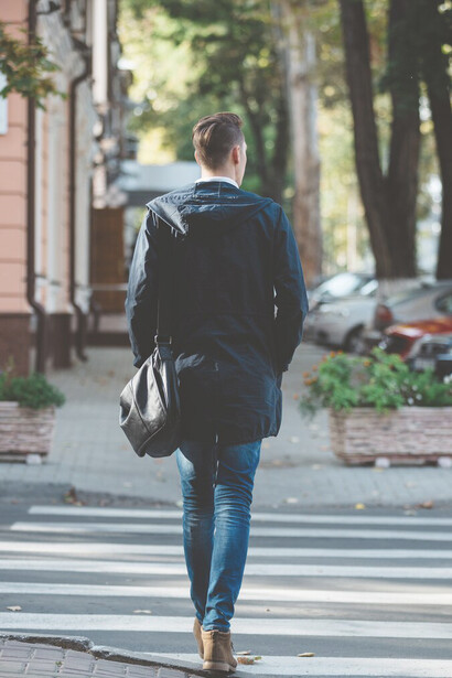 Young man enjoying an evening walk, crossing the street in a quiet neighborhood