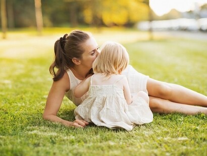 Mamma con figlia su un prato. Le mamme umane dopo la nascita dei loro piccoli devono proteggere e curare la prole molto più a lungo rispetto a tutti gli altri animali