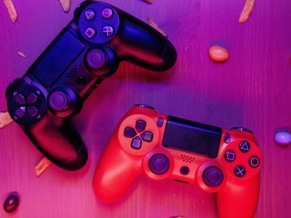 Two video game controllers under vibrant neon lights, representing the entertainment medium often blamed in the aftermath of violent tragedies