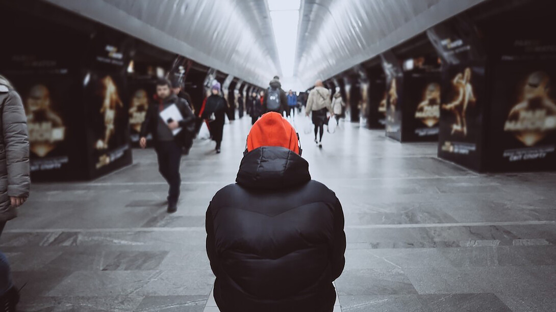 A view from behind of a man in a crowded subway, capturing the sense of alienation among commuters
