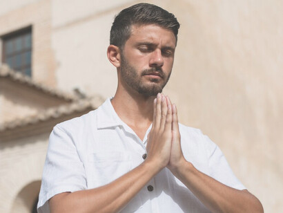 A young man in prayer, reflecting on religion and creed