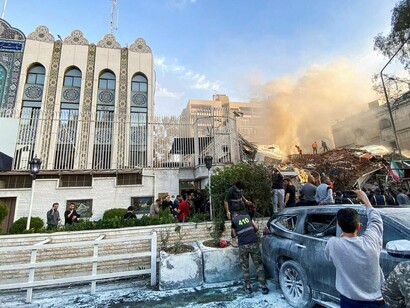 O edifício do consulado iraniano em Damasco aparece parcialmente destruído após o ataque de 1º de abril de 2024, enquanto equipes de emergência e moradores se concentram diante dos escombros. O episódio marcou uma escalada importante na confrontação entre Israel e Irã e evidenciou como a disputa regional poderia atingir diretamente instalações associadas ao Estado iraniano