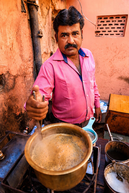 Portrait of an Indian street vendor preparing and serving chai tea