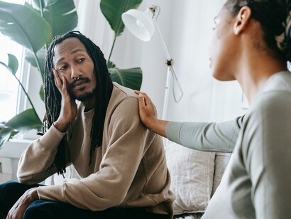 A woman showing empathy for a man sitting on a sofa 