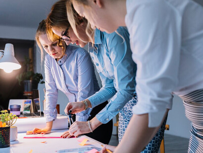 A dynamic group of young, creative businesswomen collaborating on an innovative project in a modern office