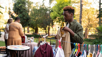 A man sifts through second-hand clothes at a yard sale, making mindful choices to resist the lure of fast fashion and support a more sustainable, circular economy