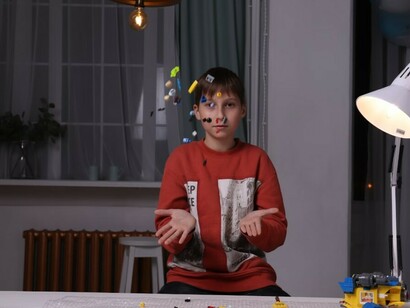 The boy is focused on arranging LEGO pieces at the table, creating his own designs
