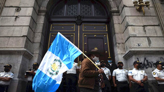 Manifestante guatemalteco transita frente al Congreso, el cual se encuentra resguardado por elementos de seguridad pública