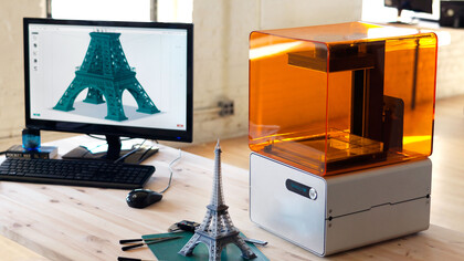 Impresora 3D junto a un modelo de la Torre Eiffel