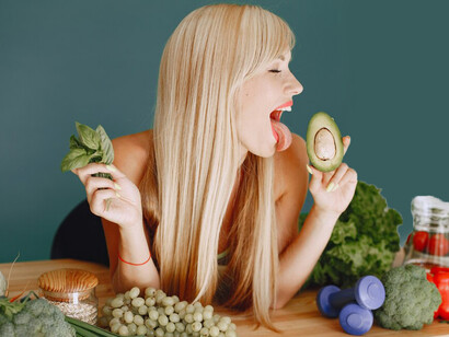 In the kitchen, a woman assembles a salad with brain-boosting foods, omega-3 sources, and adaptogens for enhanced gut health and mental clarity