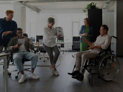 A man with a disability working confidently at his desk, surrounded by supportive colleagues, embodying diversity and inclusion at work