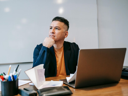 Photo of a professional man resting his fist on his chin, thoughtful and lost in thought