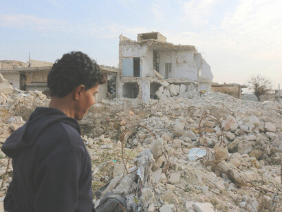 In Idlib, Idlib Governorate, Syria, a man surveys the war-torn ruins, highlighting the widespread devastation caused by conflict