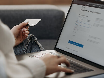 With focused determination, a woman inputs her card details into her laptop