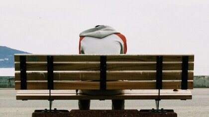 Depressed man sits on a public bench