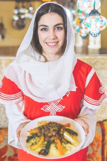A woman presenting a plate of Chelo Kebab, an iconic Iranian culinary delight
