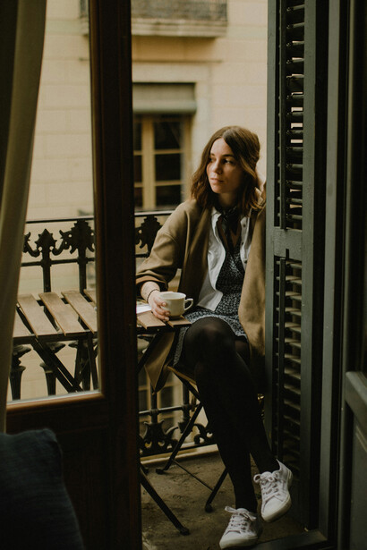 Mujer mirando la ciudad desde el balcón de una cafetería. Balconear es una manera de "pispear" con melancolía, taciturnidad y dramatismo
