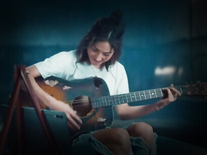 La protagonista del spot "Uncrush" tocando la guitarra
