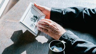 Hands holding a framed photograph, symbolizing remembrance, nostalgia, and the enduring bond with loved ones who have passed away