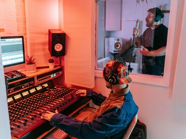 Profissional trabalha nos equipamentos de áudio durante uma sessão de gravação vocal. Entre controles, ajustes e interpretações, a ferramenta se torna parte de um processo conduzido por escolhas humanas