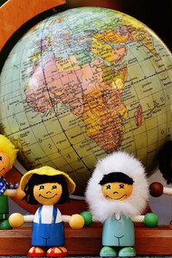Figures of children in the shapes of different nationalities in front of the world globe